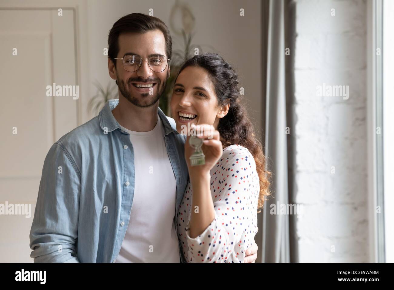 Ritratto di felici proprietari di sposi che guardano la fotocamera che mostra i tasti Foto Stock