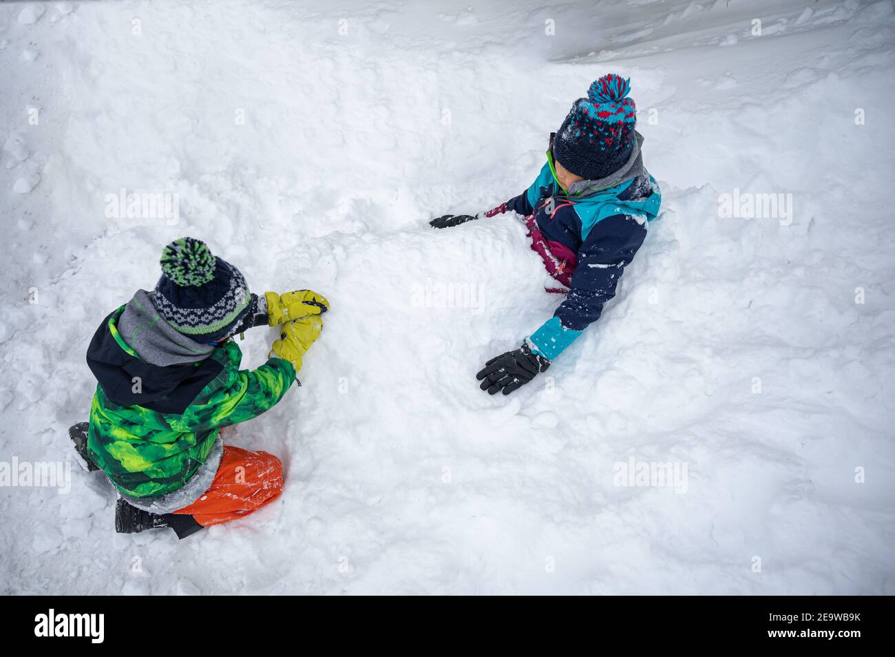 Bambini che giocano nella neve. Due bambini asiatici sepolti nella neve in inverno. Felice infanzia e divertimento. Zermatt, Svizzera. Foto Stock