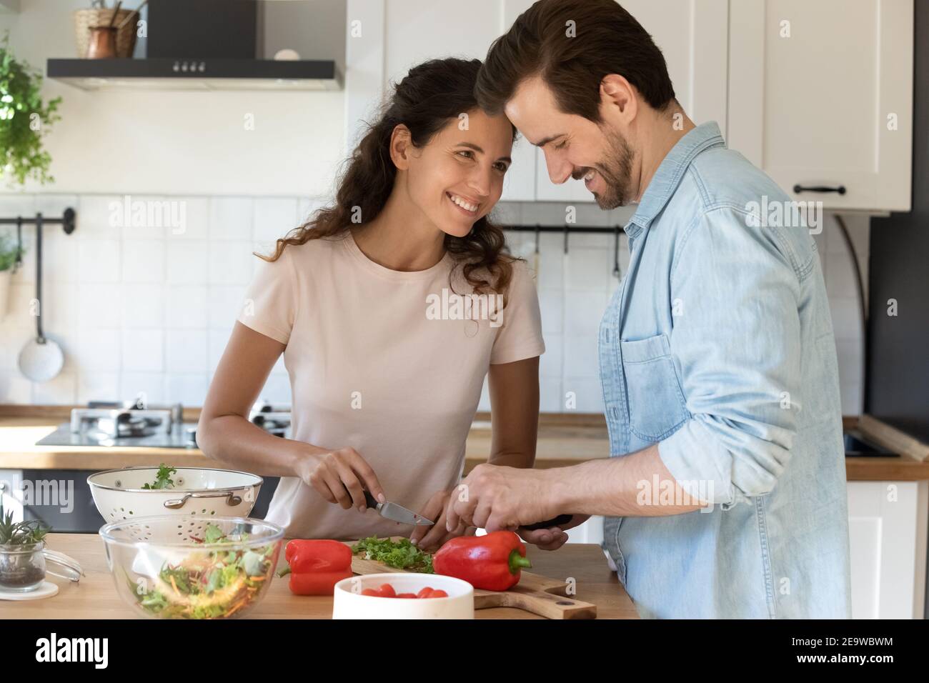 Positivi giovani sposi cucinando cibo godendo piacevole conversazione in cucina Foto Stock