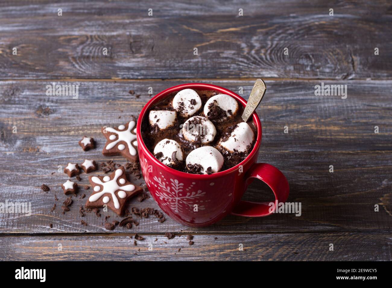 Cioccolata calda con marshmallows e cioccolato grattugiato in una tazza rossa su un tavolo di legno, stile rustico. Deliziosa bevanda di natale Foto Stock