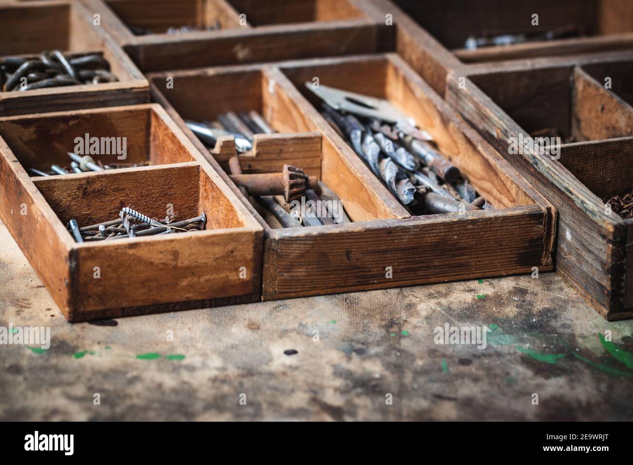 Cassetta attrezzi con chiodi, viti e punta da trapano su tavola di legno. Attrezzature industriali arrugginite in officina di carpenteria, fuoco selettivo Foto Stock