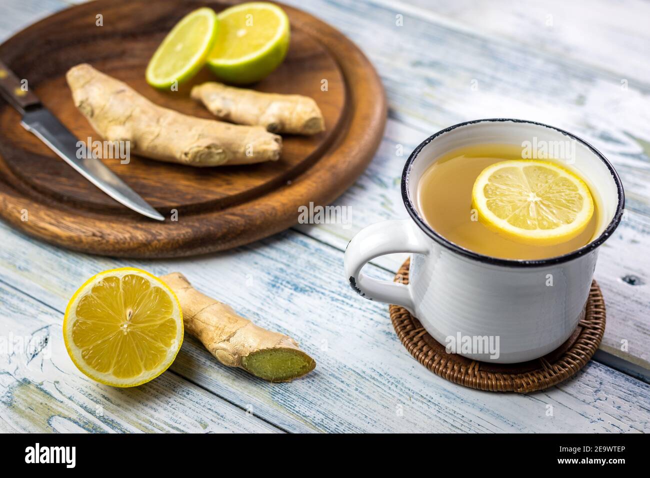 Radice di zenzero e tè caldo con fetta di limone in tazza bianca. Concetto di stile di vita sano. Bevanda calda in teacup su tavolo di legno Foto Stock
