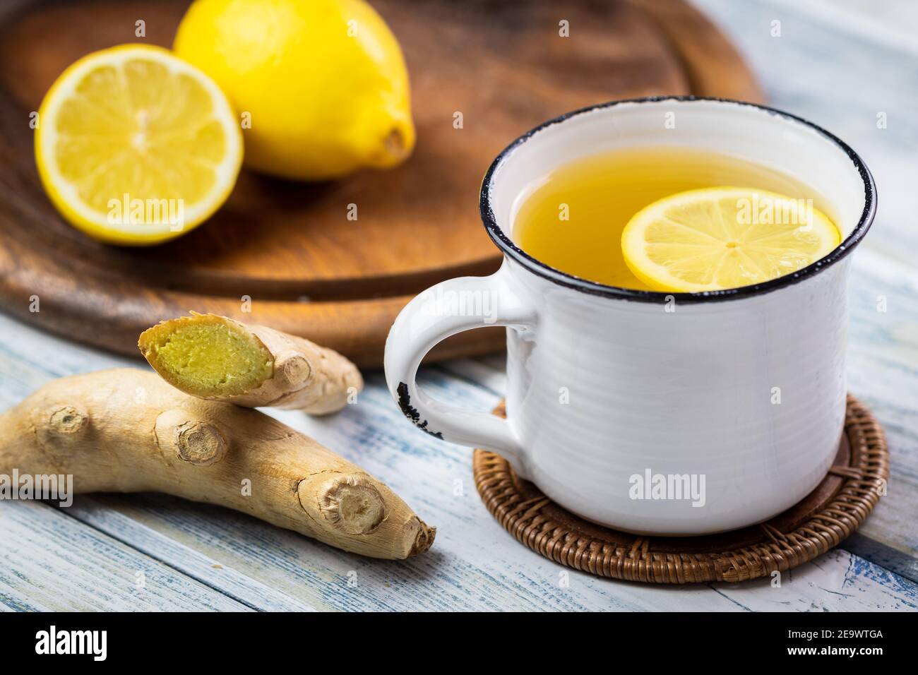 Radice di zenzero e tè caldo con fetta di limone in tazza bianca. Concetto di stile di vita sano. Bevanda calda in teacup su tavolo di legno Foto Stock