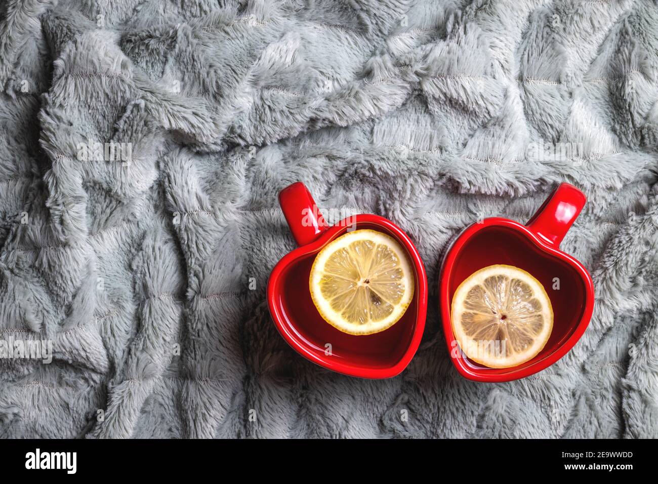 Due bevande calde e coperta. Tazza da tè a forma di cuore come simbolo di giorno di amore o di valentine. Tè al limone in tazza Foto Stock