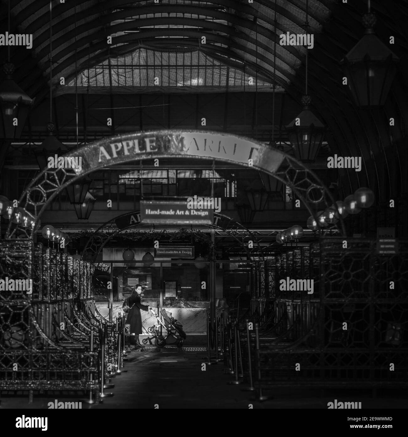 Una donna spinge un pRAM attraverso una striscia di luce a Covent Garden, Londra. Foto Stock