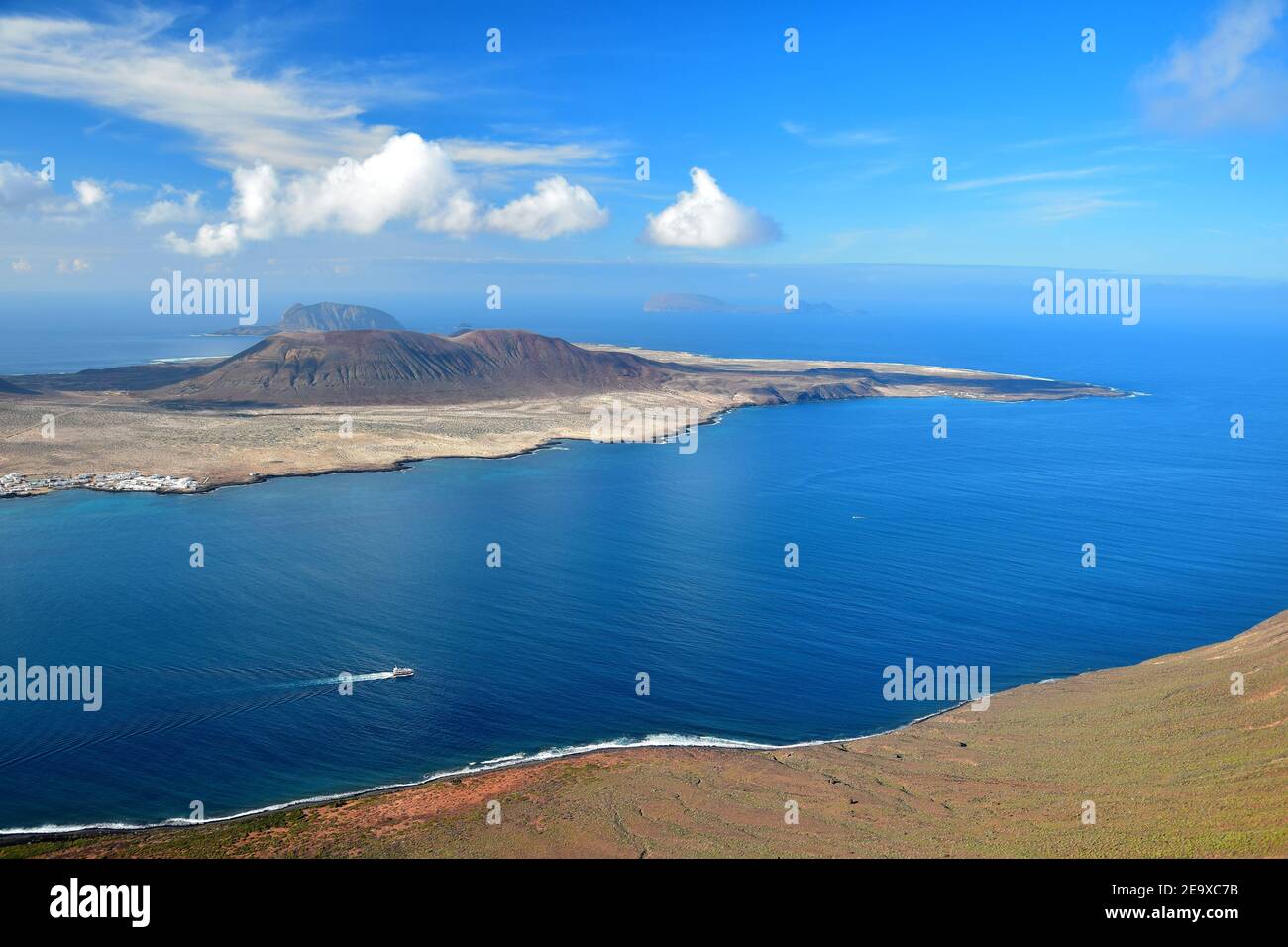La Graciosa, una piccola isola vulcanica nel nord di Lanzarote, Spagna. Oceano blu e un cielo blu con alcune nuvole bianche. Lontano sullo sfondo l'Isl Foto Stock
