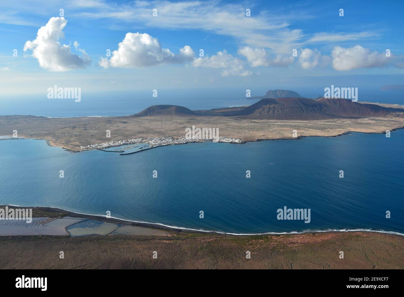 La Graciosa, una piccola isola vulcanica nel nord di Lanzarote, Spagna. Oceano blu e un cielo blu con alcune nuvole bianche. Lontano sullo sfondo l'Isl Foto Stock