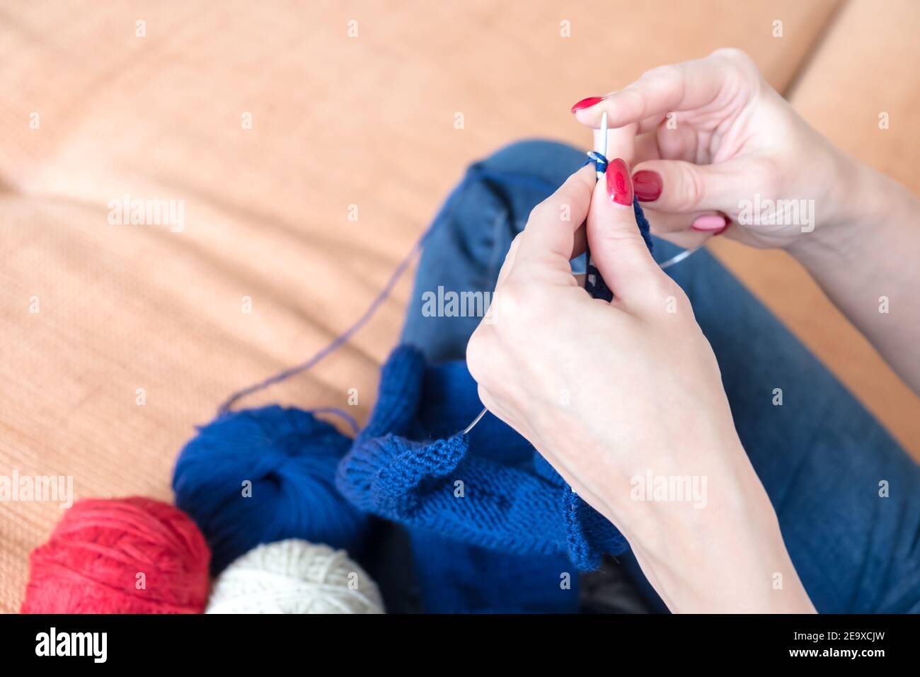 Primo piano di mani femminili che tessano una sciarpa blu. Foto Stock