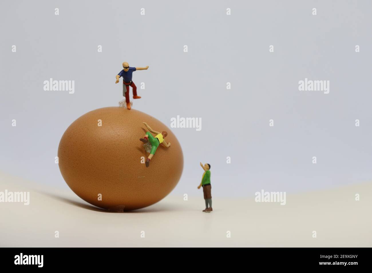 Modellare gli arrampicatori che si equilibrano su un uovo. Foto Stock
