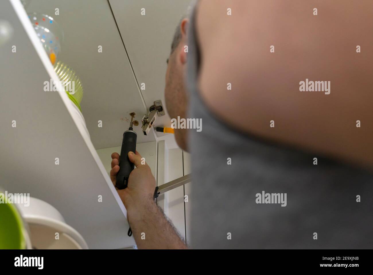 un uomo che fissa una porta di armadio in cucina. Foto Stock