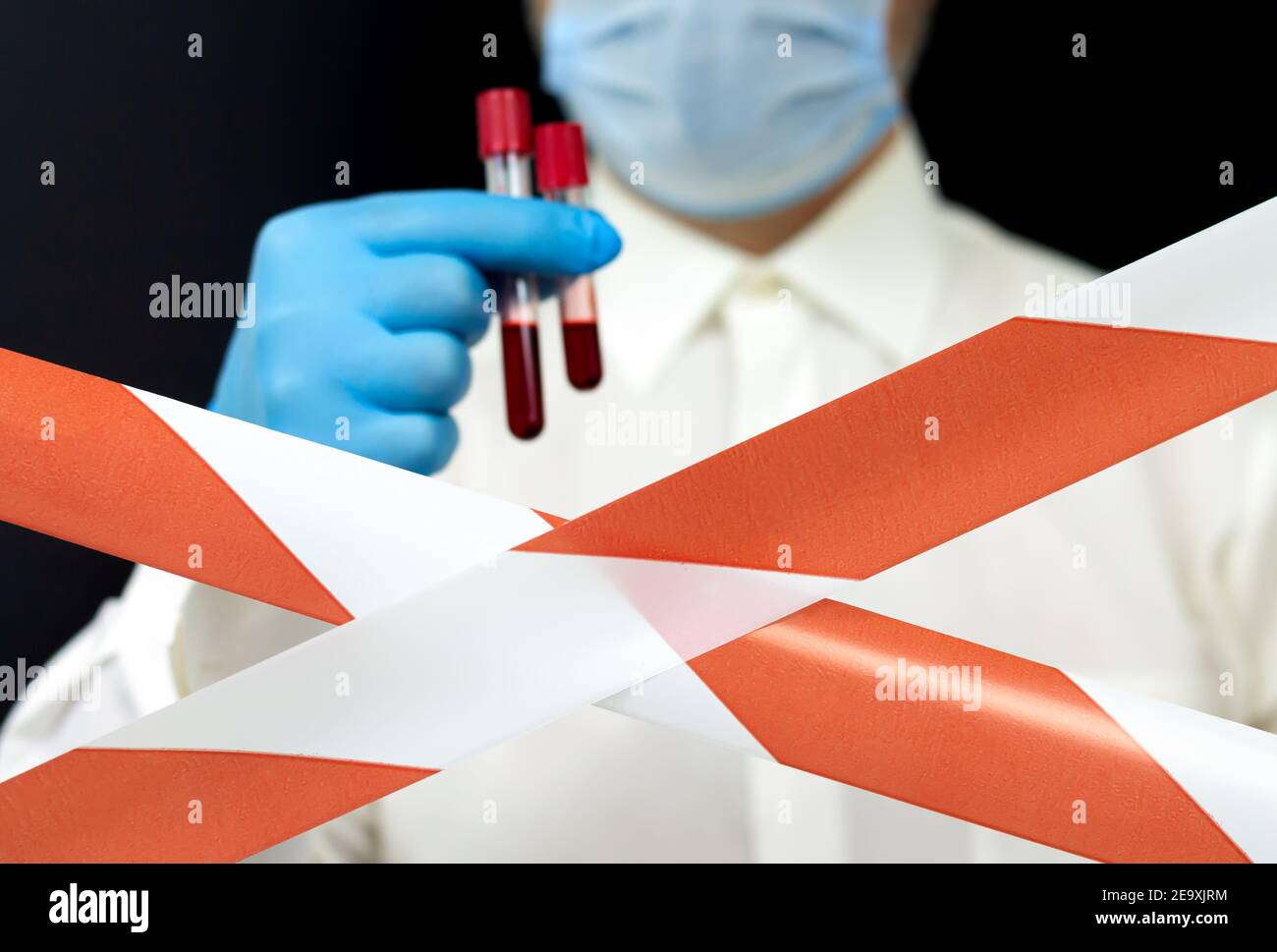 Armi biologiche segrete contro gli esseri umani, epidemia di virus concetto. Matracci di sangue di Holdinf per i medici dietro i nastri di avvertenza Foto Stock