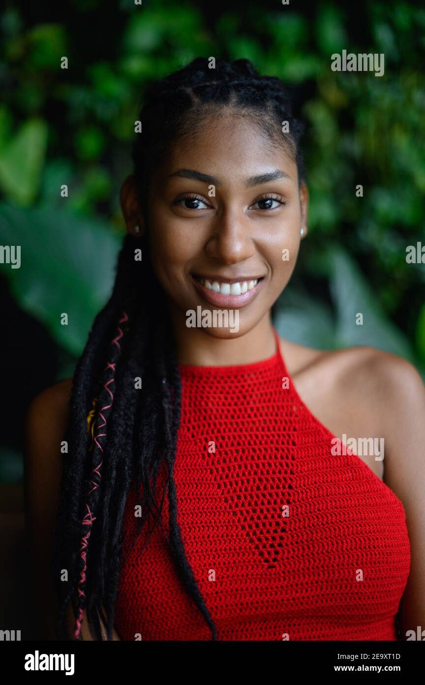 Ritratto di felice giovane afrolatina con dreadlock in un crochet rosso top, Colombia Foto Stock