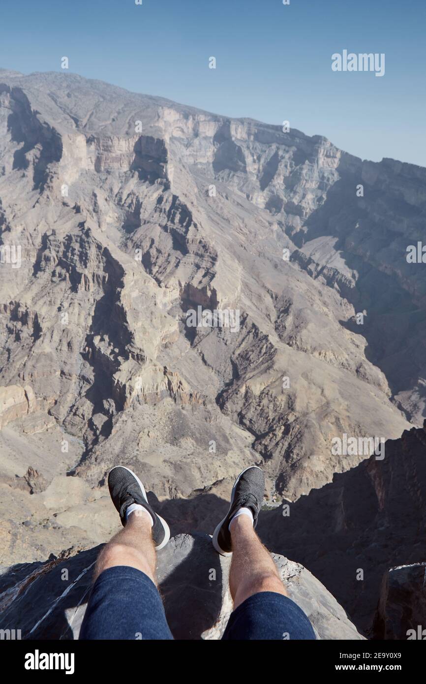 Giovane uomo che riposa al bordo della scogliera. Vista mozzafiato personale con canyon, Jebel Shams in Oman Foto Stock