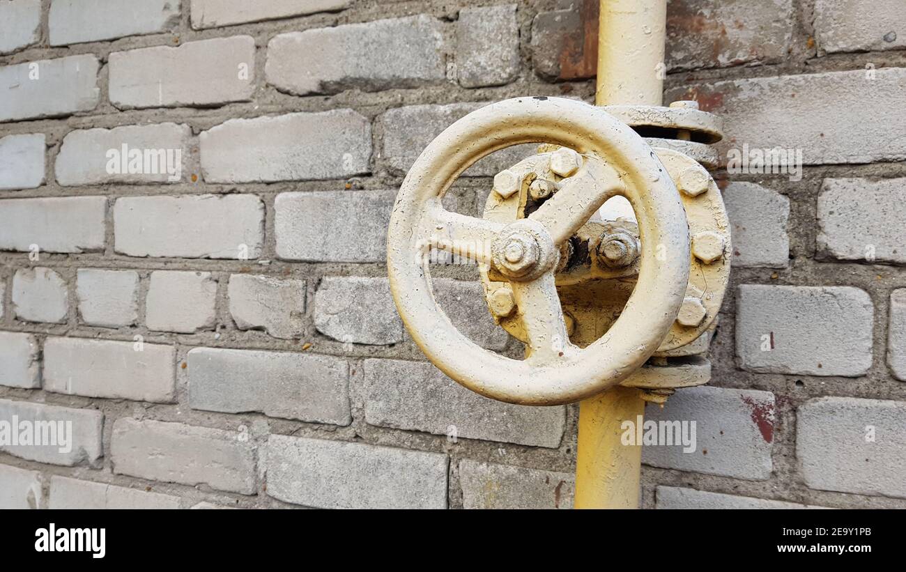 valvola del gas gialla sulla conduttura lungo la parete dell'edificio. Foto Stock