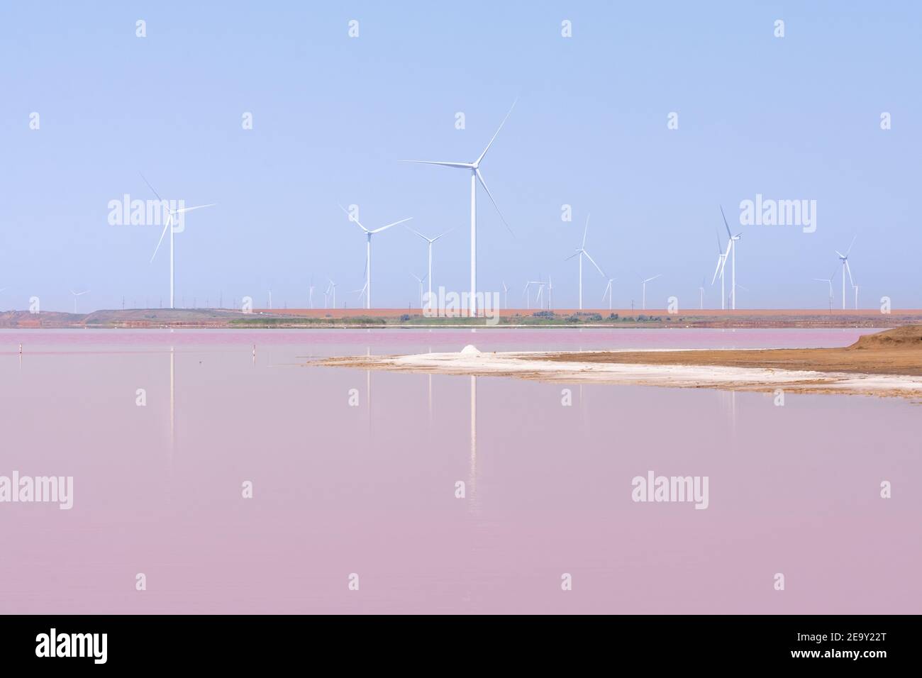 Turbine eoliche che riflettono nelle pianure saline. Acqua colorata con alghe rosa. Orientamento verticale. Foto Stock