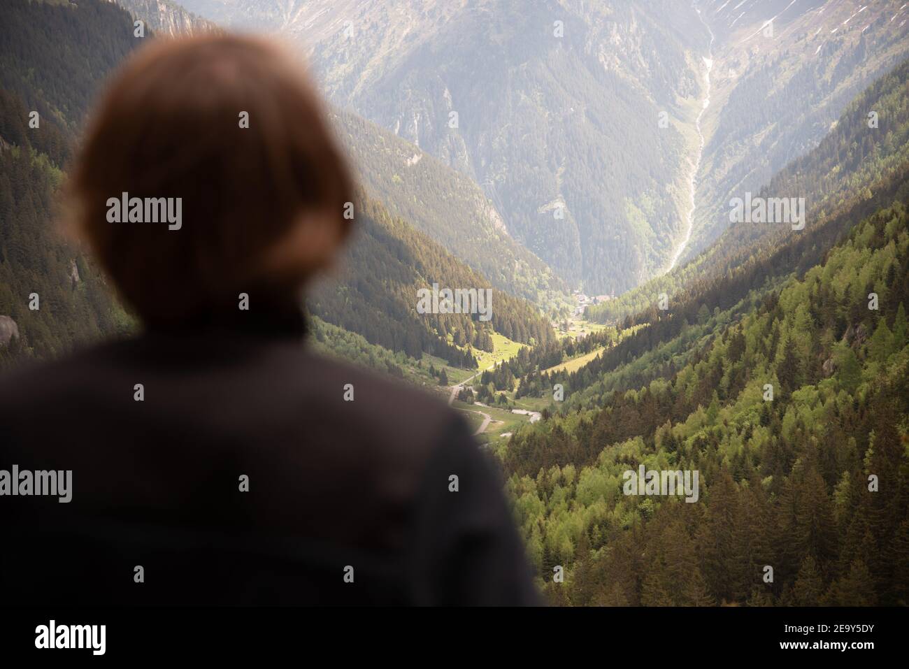 Uomo guardando bellissimo paesaggio montano con valle e foreste Foto Stock