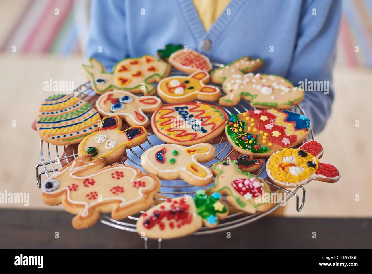 Primo piano di donna che regge vassoio con decorate biscotti al forno preparazione Per Pasqua Foto Stock