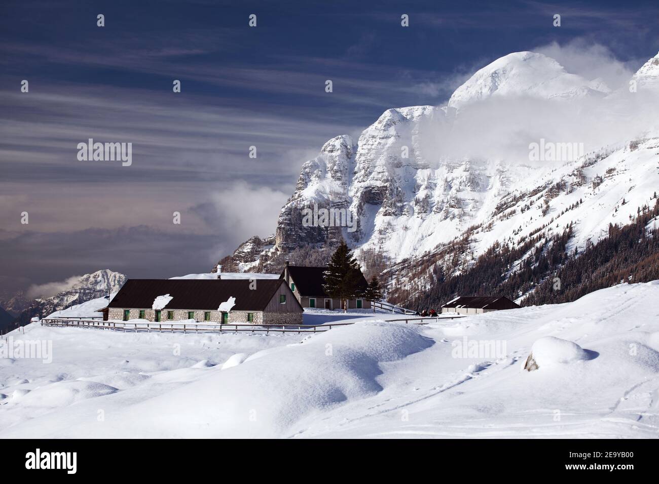 Fattoria di montagna in inverno con neve dintorni e alta montagna sfondo Foto Stock