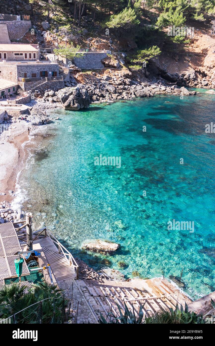 Onde che si infrangono sulla costa rocciosa delle montagne di Maiorca sullo sfondo, giornata di sole, nelle isole Baleari, Spagna Foto Stock