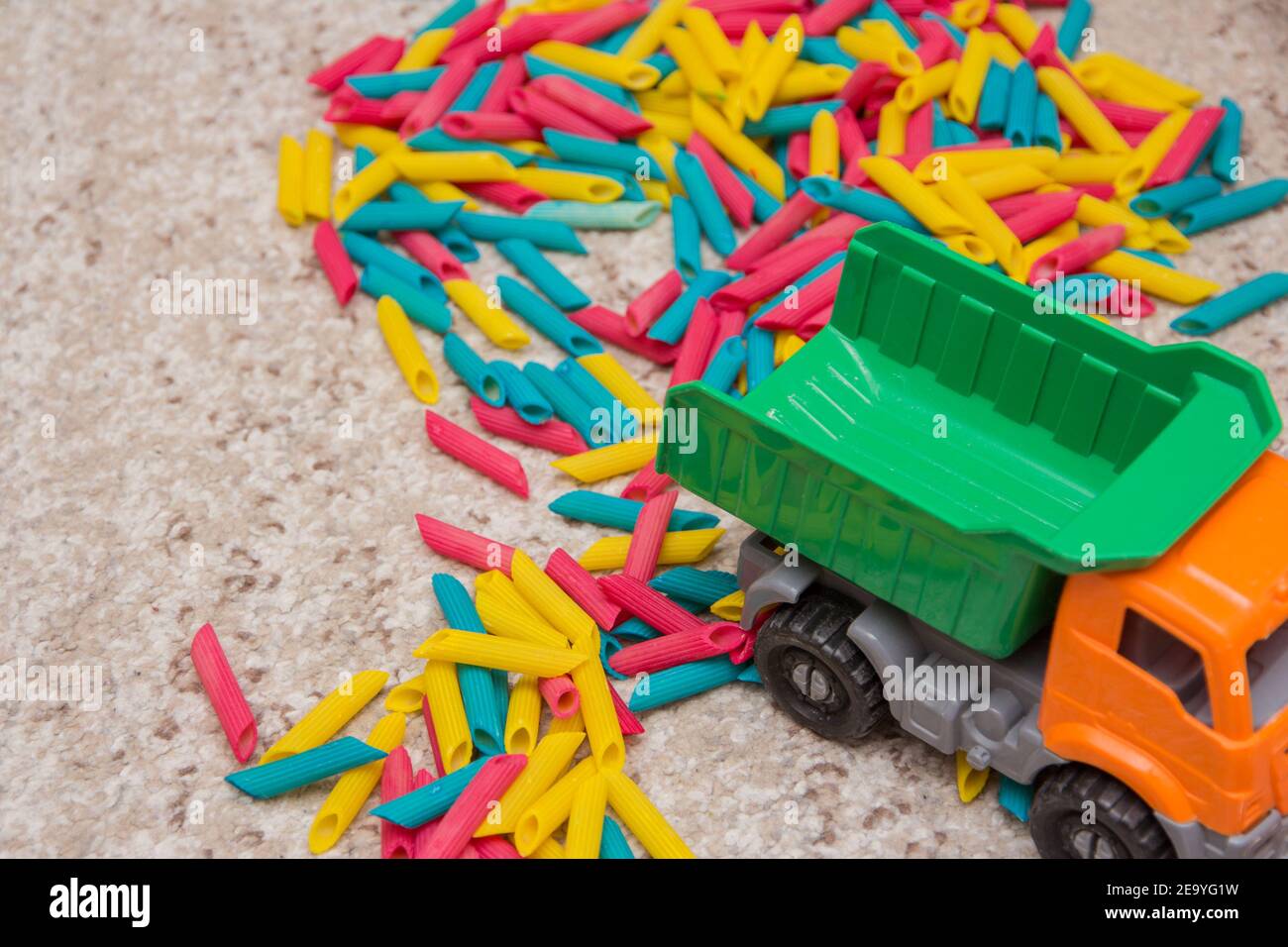 Gioco per bambini costituito da tagliatelle dipinte in diversi colori e un camion giocattolo. Giochi per bambini. Sviluppo di bambini. Giochi per bambini tattili Foto Stock
