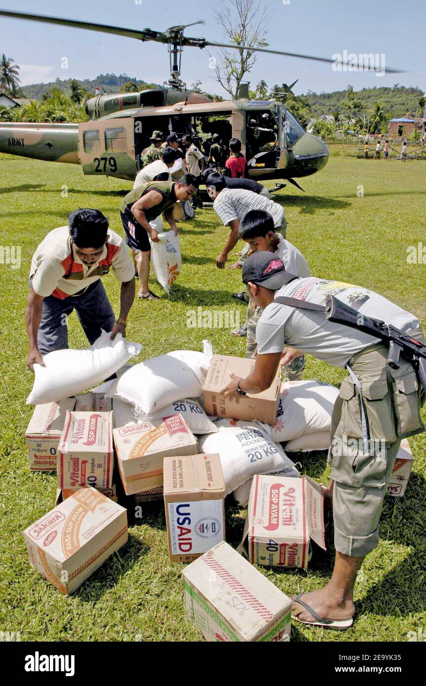 I cittadini indonesiani scaricano le forniture da un elicottero militare straniero UH-1 Iroquois a Lamno, Sumatra, Indonesia. Gli elicotteri assegnati alla Carrier Air Wing Two (CVW-2) e i marinai di Abraham Lincoln stanno sostenendo l'operazione Unified Assistance, l'operazione umanitaria sulla scia dello tsunami che ha colpito il Sud-Est asiatico. Foto di Jordon R. Beesley /USN via ABACA. Foto Stock