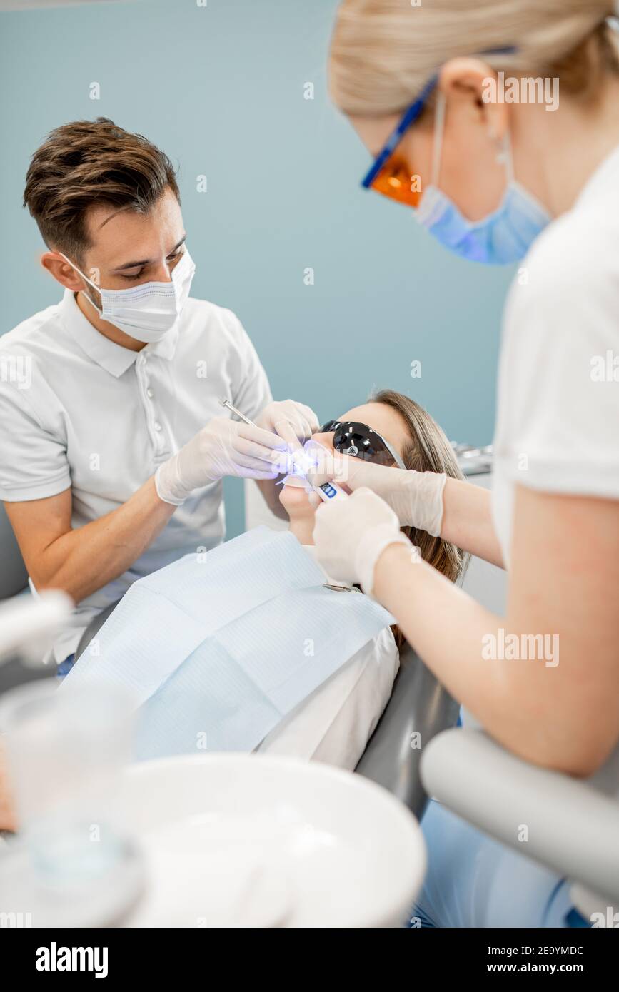 Dentista maschile e assistente utilizzando luce di cura dentale Foto Stock