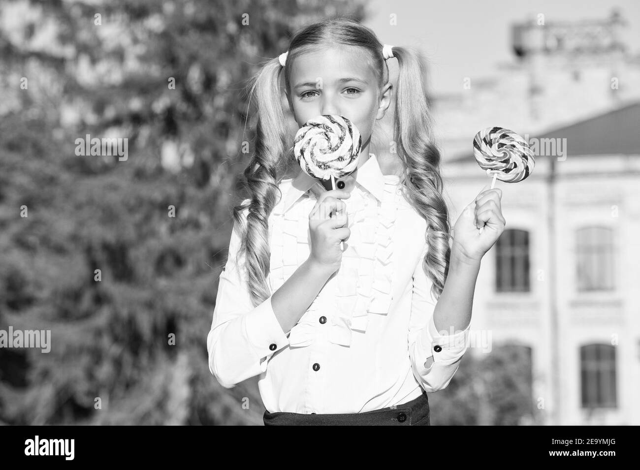 Felice studentessa mangia coloratissimi lecca all'aperto, concetto di dessert yummy. Foto Stock