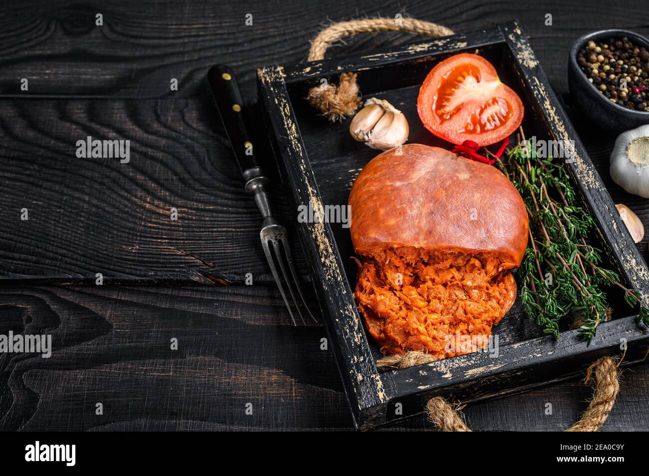 Mallorcan Sobrassada salumi di carne di maiale in un vassoio di legno sfondo di legno nero. Vista dall'alto. Spazio di copia Foto Stock