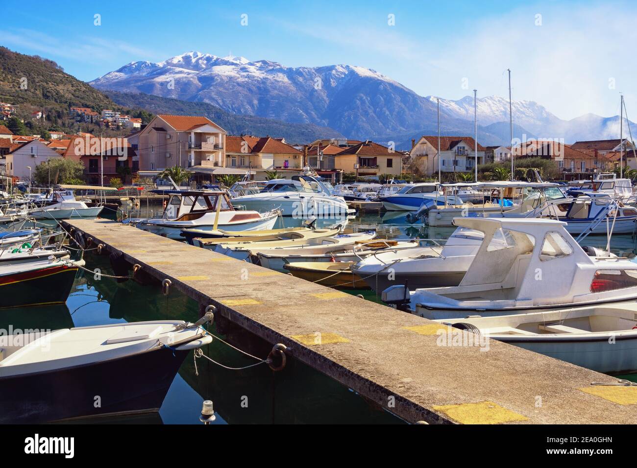 Barche da pesca nel porto. Paesaggio mediterraneo invernale. Montenegro. Vista di Marina Kalimanj nella città di Tivat contro la montagna Lovcen innevata Foto Stock