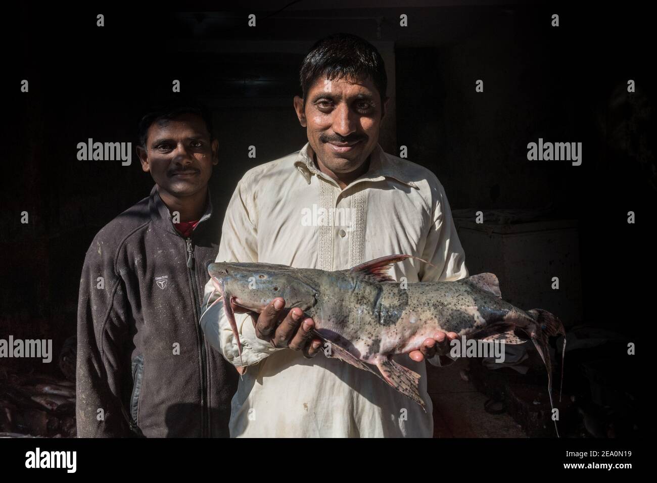 Uomo con orgoglio tenere un pesce al mercato del pesce vicino Circular Road, Lahore, Punjab, Pakistan Foto Stock