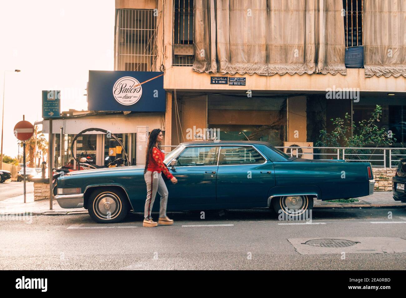 Una donna passa davanti a una classica Cadillac Coupe Deville a Beirut, Libano Foto Stock