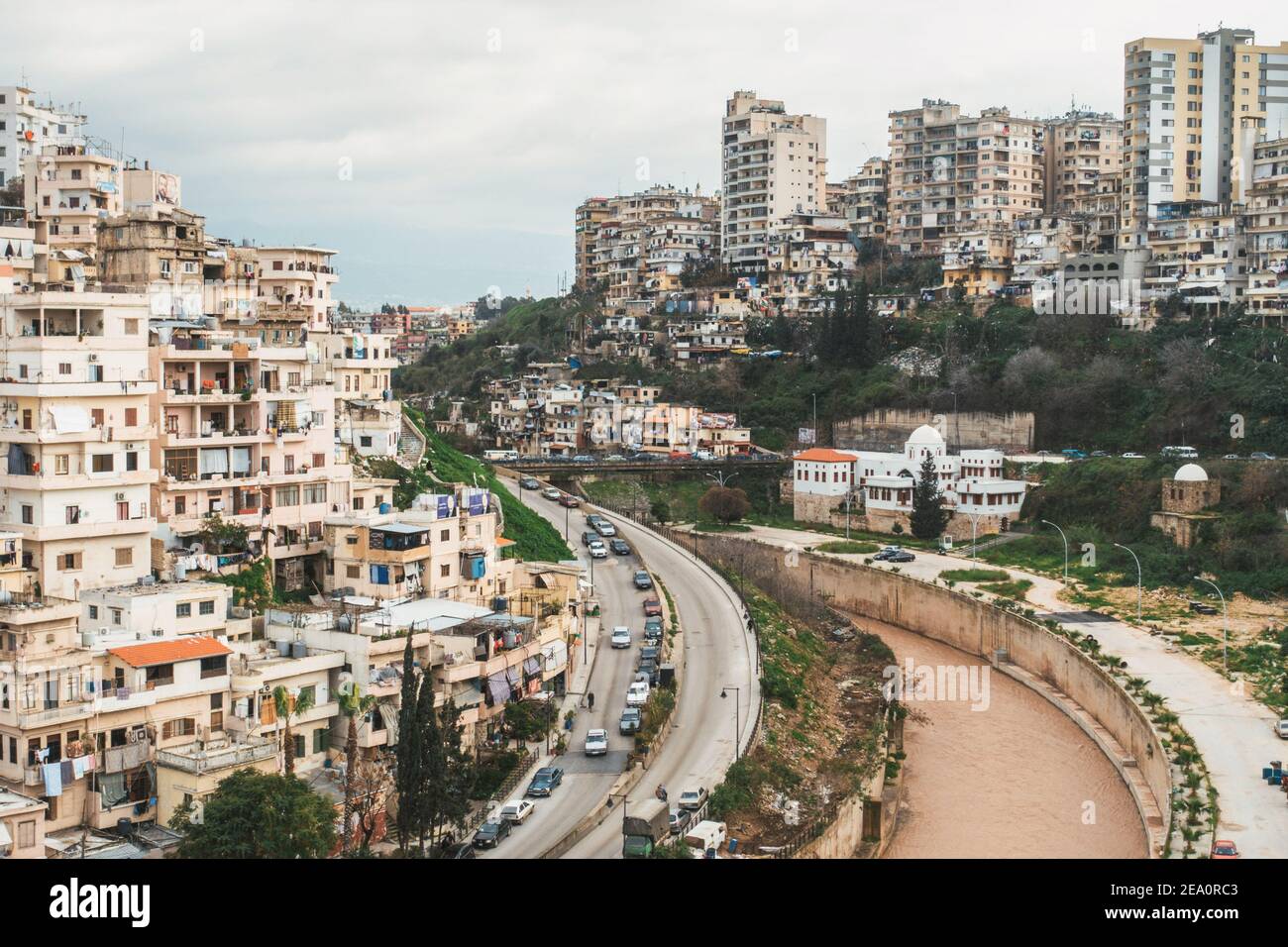 Si affaccia sulle case densamente accatastate di Tripoli, in Libano. Il fiume Abou Ali scorre intorno a una curva rinforzata Foto Stock