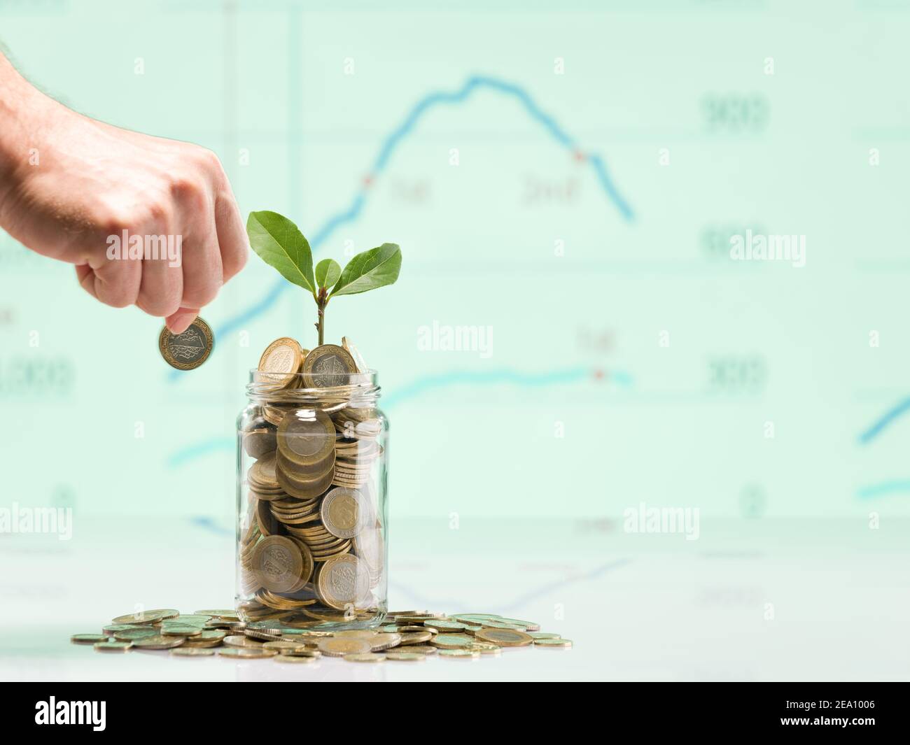 Mano della persona che tiene la moneta da mettere in vaso di vetro. Monete turche in vasi. Impianti in vaso e turco 1 TL monete concetto di risparmio e di finanza. Foto Stock