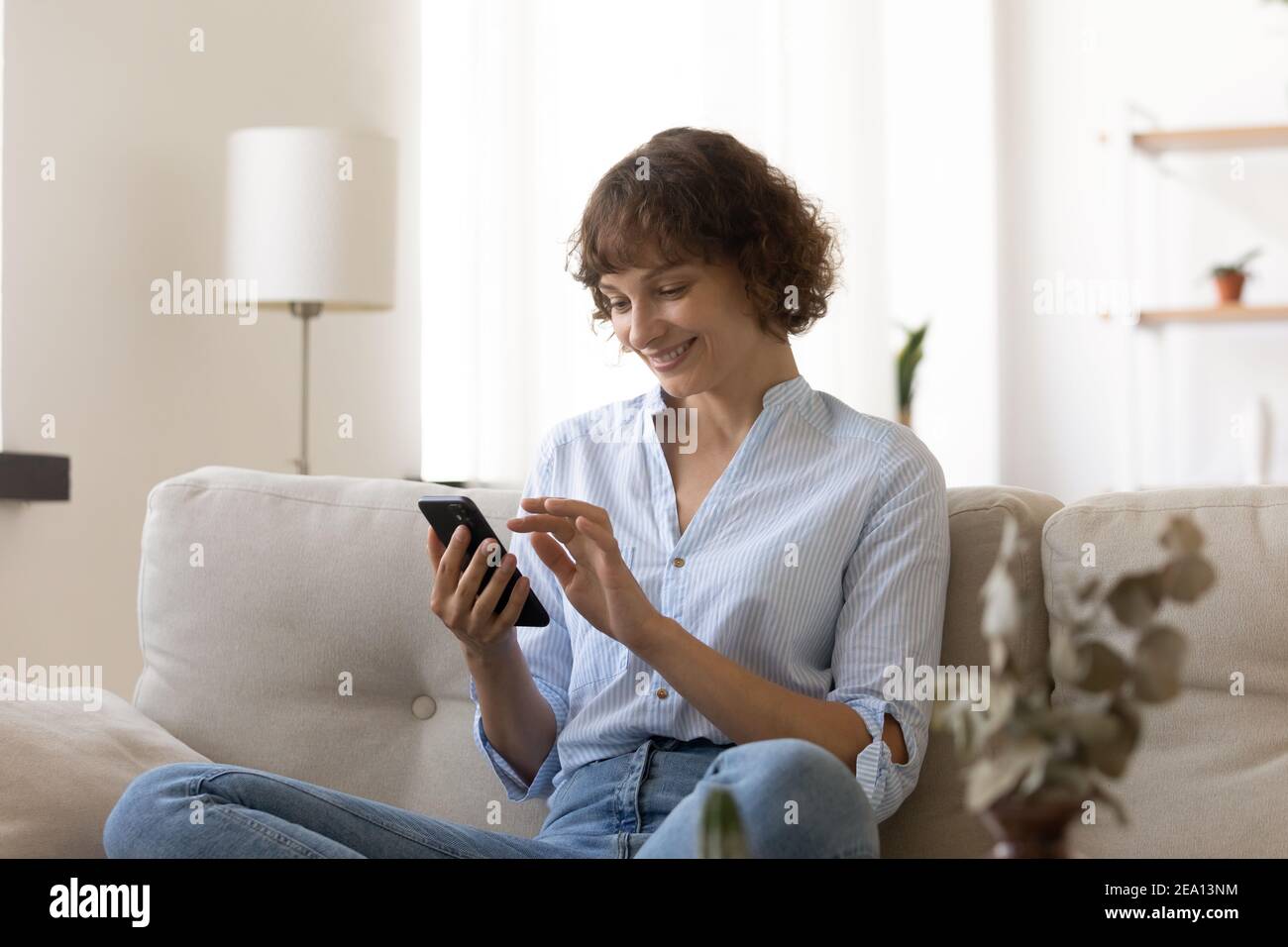 Donna felice usa il telefono cellulare shopping online da casa Foto Stock