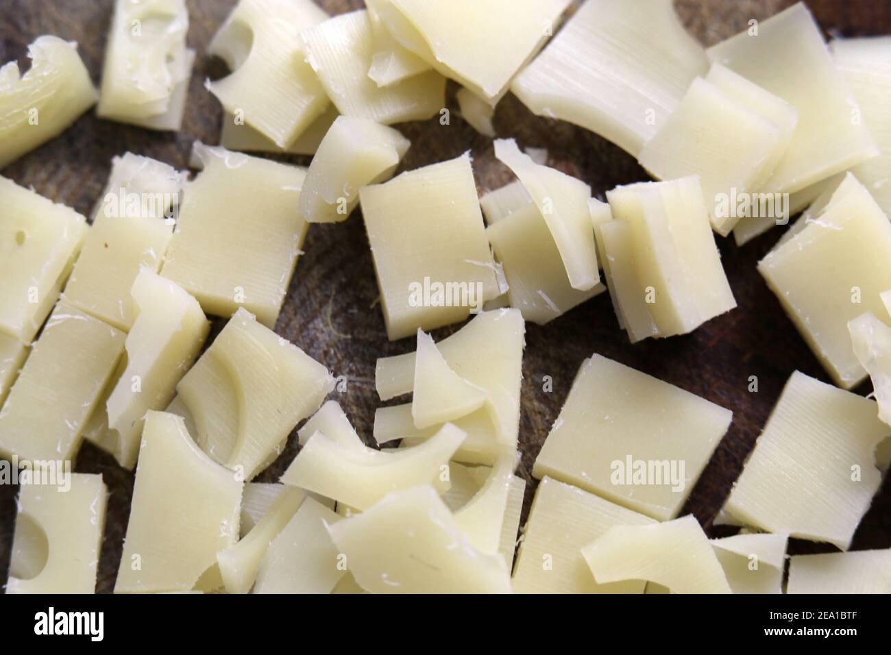 Preparazione degli alimenti per la cottura: Pezzi di formaggio a basso contenuto di grassi tritati in un primo piano. Prodotto caseario sano da utilizzare per un omelette. Cucina casalinga. Foto Stock