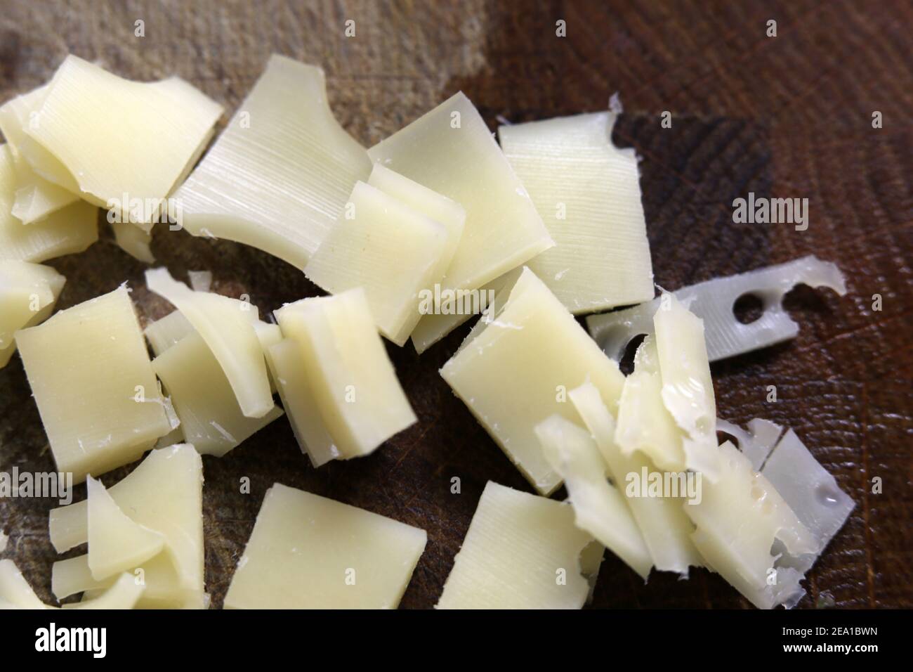 Preparazione degli alimenti per la cottura: Pezzi di formaggio a basso contenuto di grassi tritati in un primo piano. Prodotto caseario sano da utilizzare per un omelette. Cucina casalinga. Foto Stock