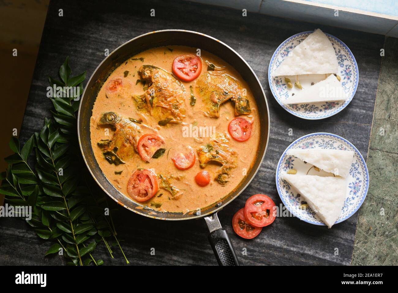 Vista dall'alto speziato stile Kerala stufato di curry di pesce e Appam Pesce Molee Meen Moilee cibo Indiano. Curry di pesce con peperoncino rosso al latte di cocco, foglie di curry, pomodoro. Foto Stock