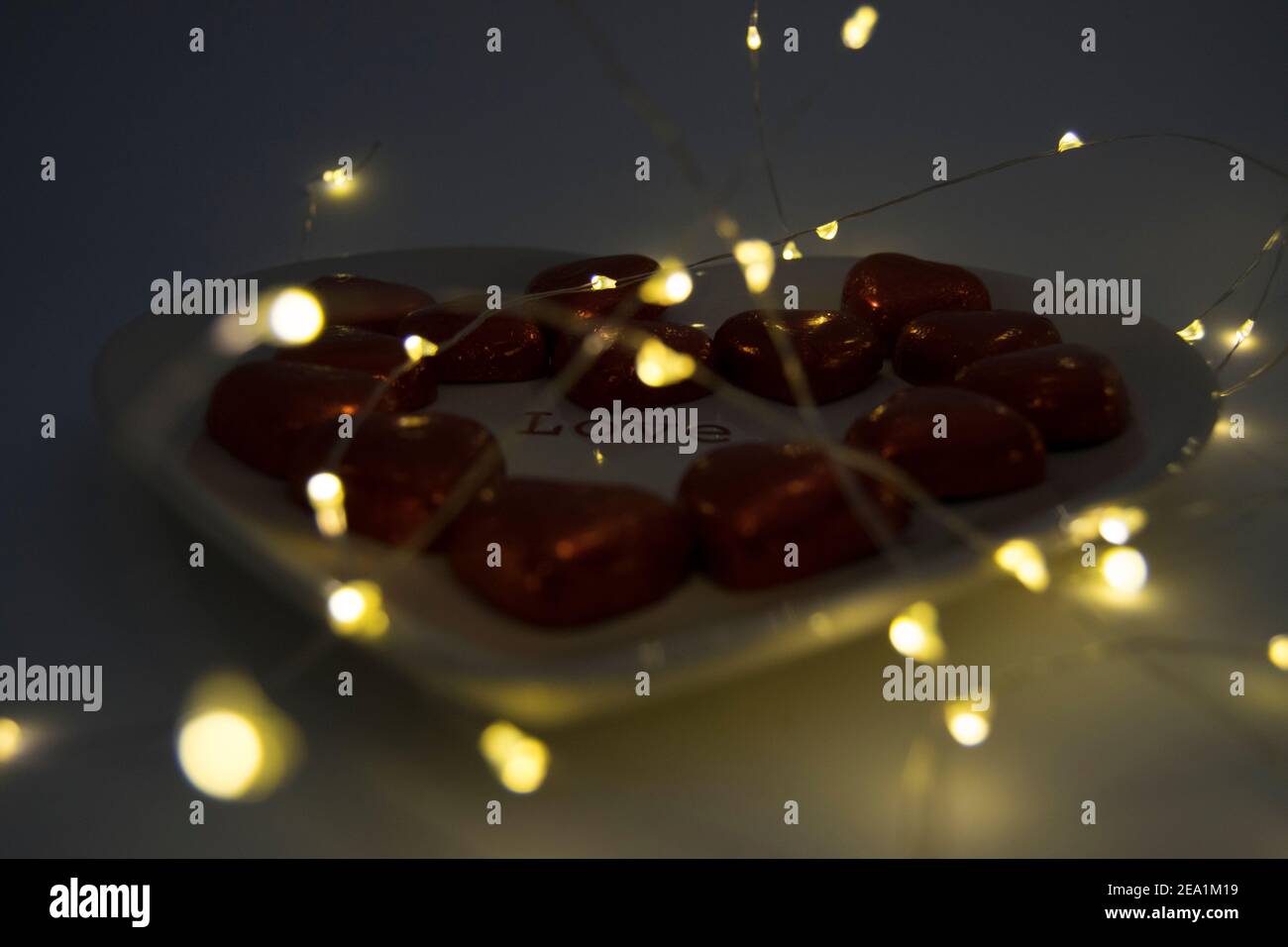 Cuori di cioccolato su un piatto a forma di cuore con luci fairy Foto Stock