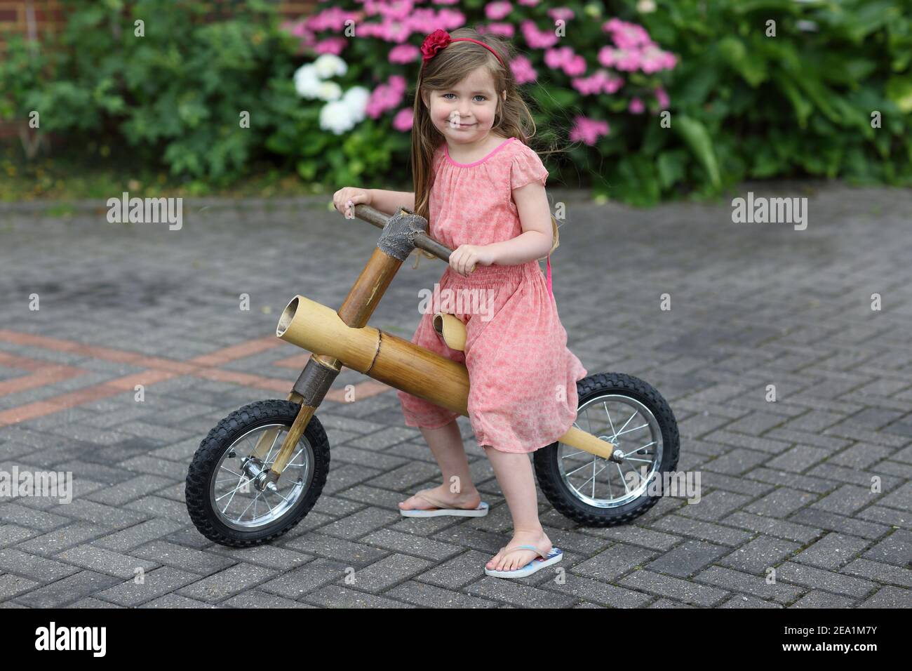 Caucasica ragazza che guida bici equilibrio fatto di bambù all'aperto in una giornata di sole. Sta imparando nuove abilità. Foto Stock