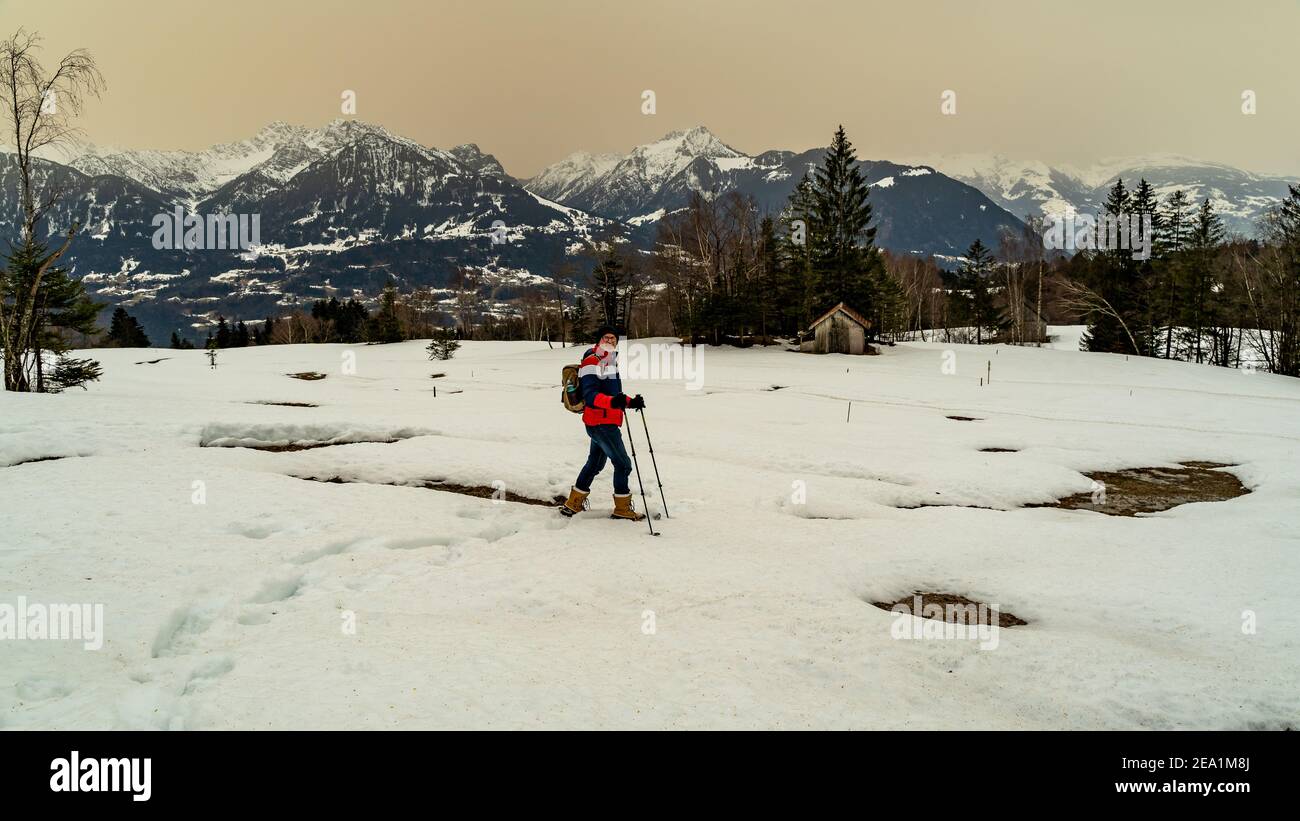 Escursione con le racchette da neve sul Walgau nel Vorarlberg innevato. Schneeschuhwanderung im Hochmoor über Sateins mit Saharasand am Himmel. Stadel Foto Stock