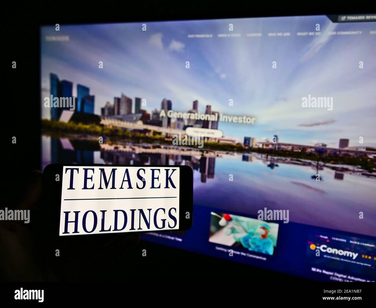 Persona che detiene smartphone con il logo della società di investimento Singaporean Temasek Holdings sullo schermo di fronte al sito web. Mettere a fuoco il display del telefono. Foto Stock
