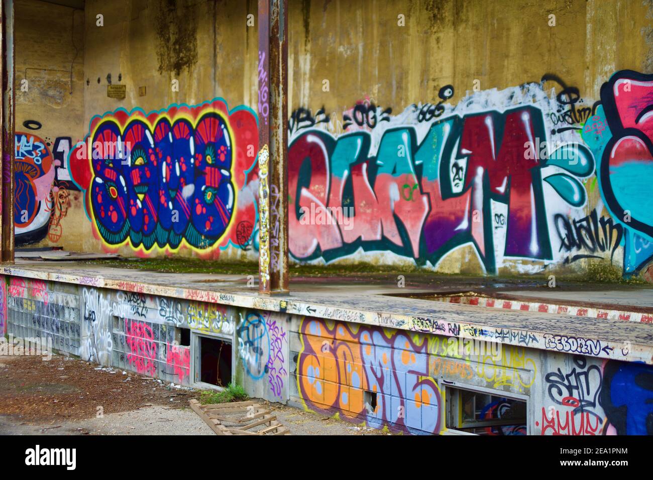Coloratissima parete in una fabbrica abbandonata su cemento Foto Stock