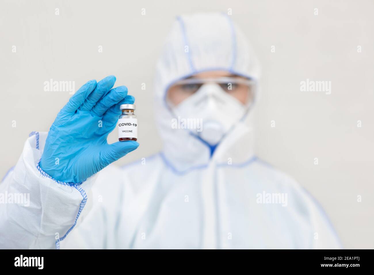 Medic in tuta, guanti, maschera protettiva e occhiali di protezione contiene il vaccino contro Covid-19 Foto Stock