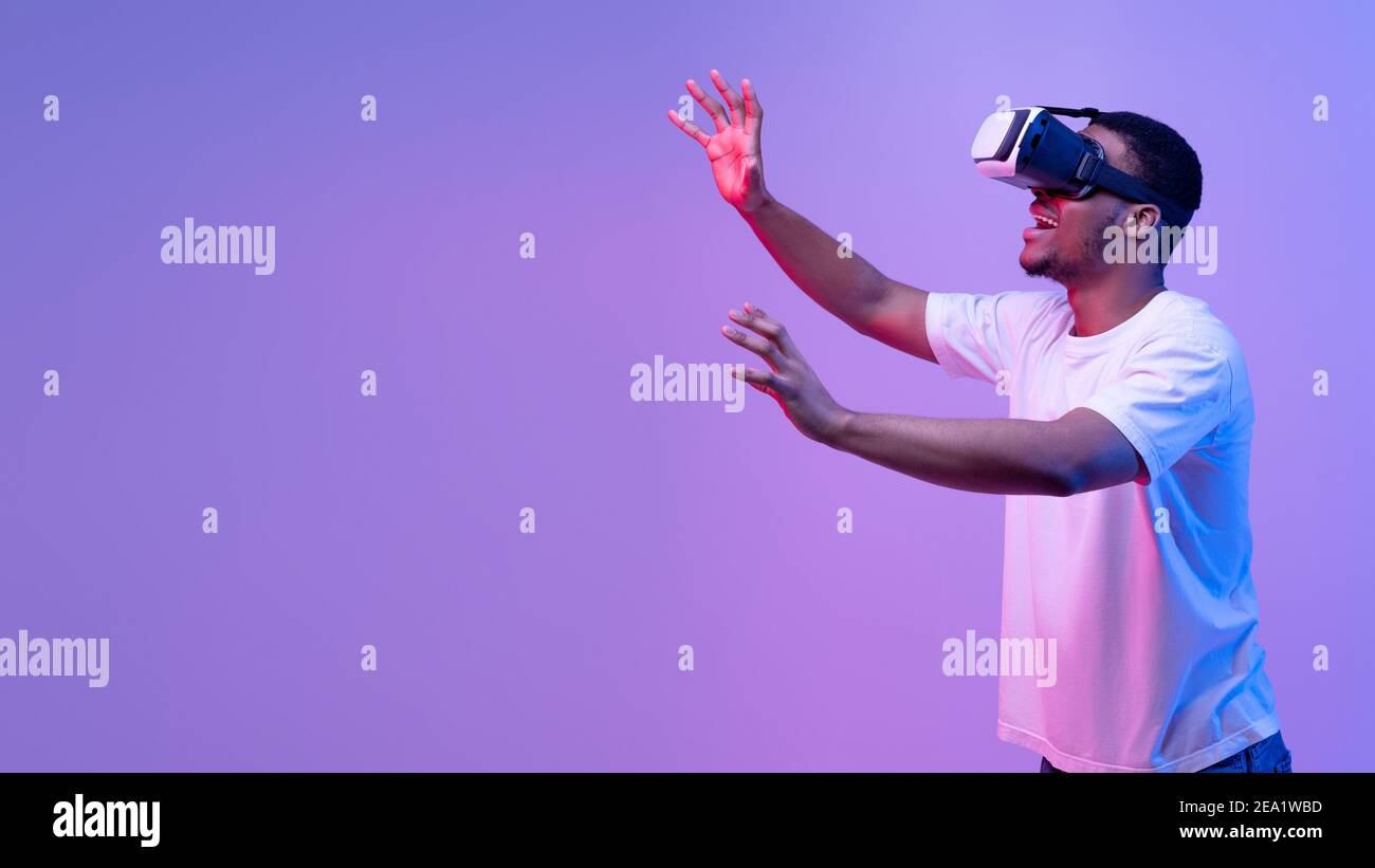 Giovane ragazzo africano che ha esperienza di realtà virtuale in occhiali VR, Neon Light Foto Stock