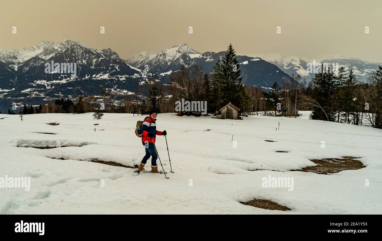 Escursione con le racchette da neve sul Walgau nel Vorarlberg innevato. Schneeschuhwanderung im Hochmoor über Sateins mit Saharasand am Himmel. Stadel Foto Stock