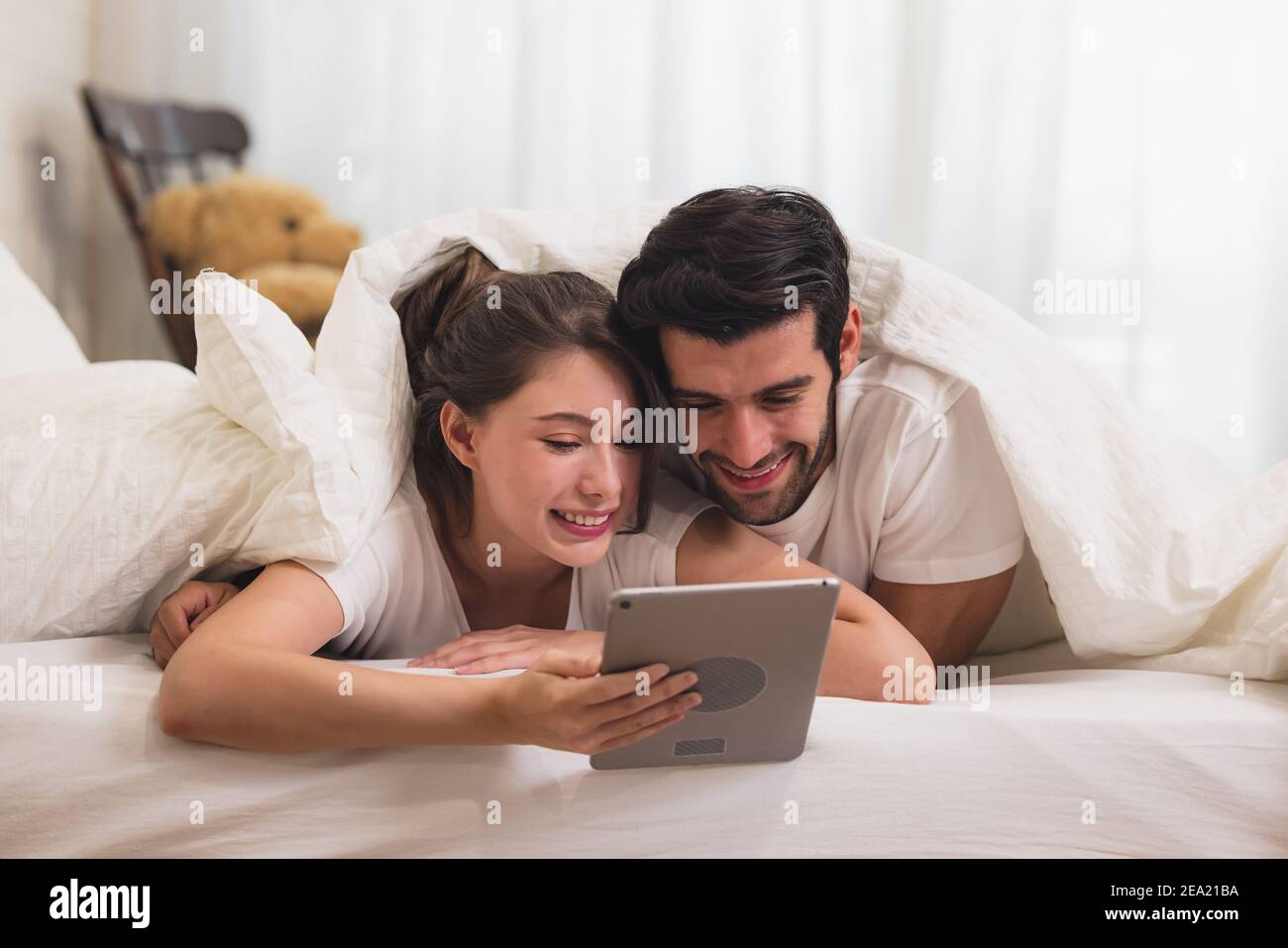 Primo piano giovane dolce coppia sul letto guardando qualcosa sul Tablet  Gadget, rilassarsi in camera da letto Foto stock - Alamy
