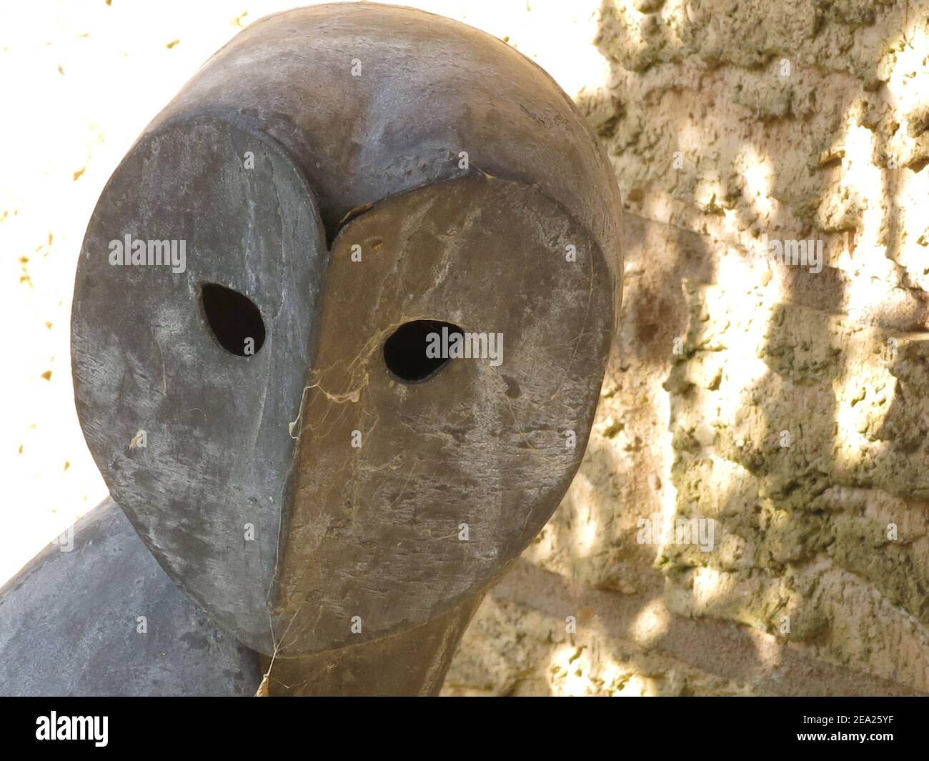 La testa di un gufo in una scultura da giardino in metallo con i suoi occhi vuoti, leggermente spooky, sempre vigili. Foto Stock