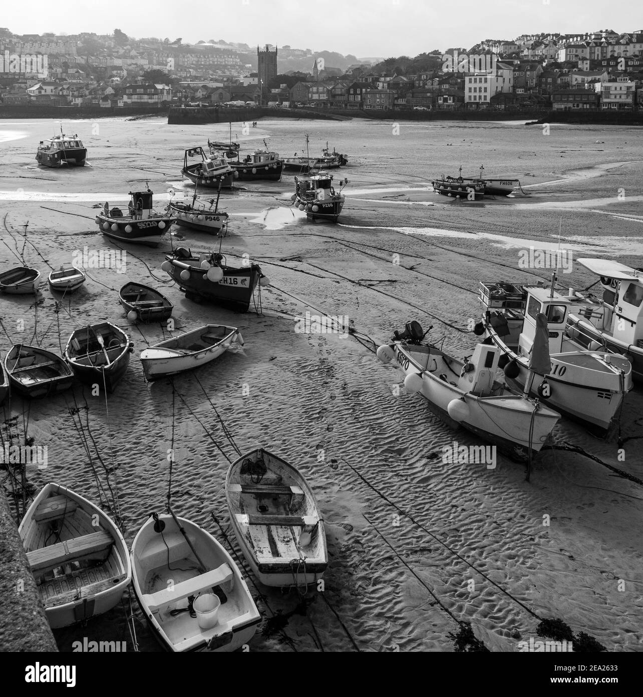 Ampia vista angolata di molte barche da pesca e altre adagiato sulla sabbia nel porto di St Ives. Vuoto e silenzioso a causa del blocco pandemico globale Covid-19 Foto Stock