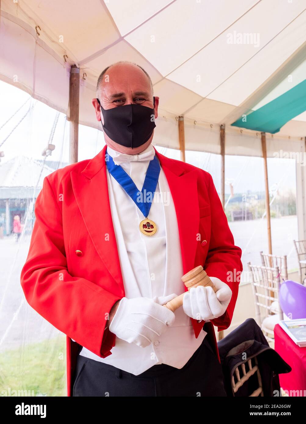 Maestro di cerimonie in piena regalia compreso Covid 19 maschera contro la diffusione di Coronavirus, tenendo il suo gavel, mentre in piedi in un marchese. Foto Stock