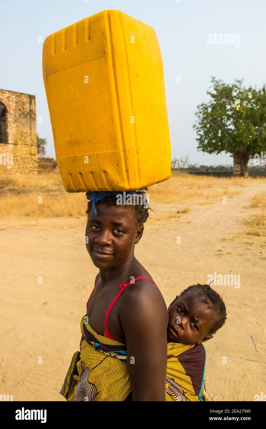 Donna con il suo bambino sulla schiena che porta un tanica d'acqua sulla testa, Massangano, Cuanza Norte, Angola Foto Stock